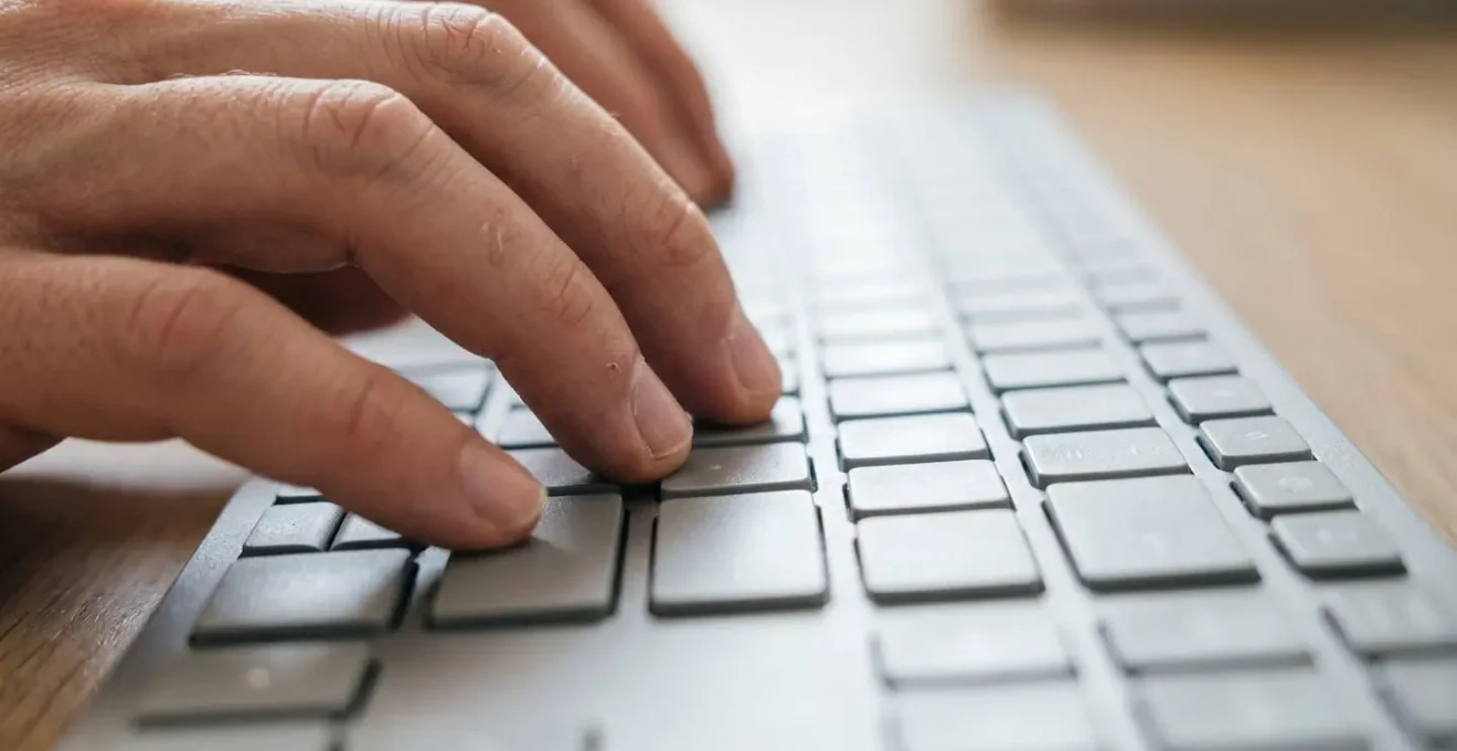 Gros plan sur une main tapant sur un clavier d'ordinateur moderne avec un arrière-plan flouté